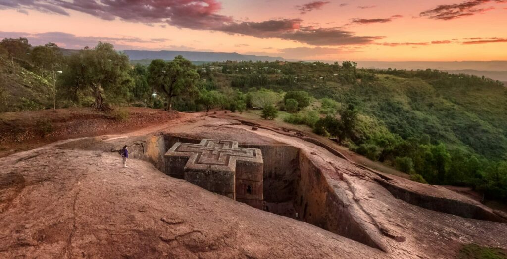 Vue dee loin d'une personne devant une église monolithe médiévale de Lalibela en Ethiopie.
