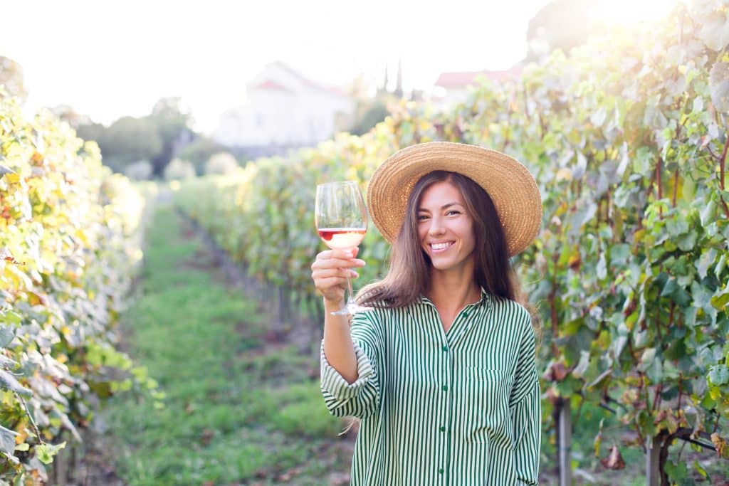 Woman,With,Wineglass,Of,Pink,Wine,In,Vineyard,At,Sunset.