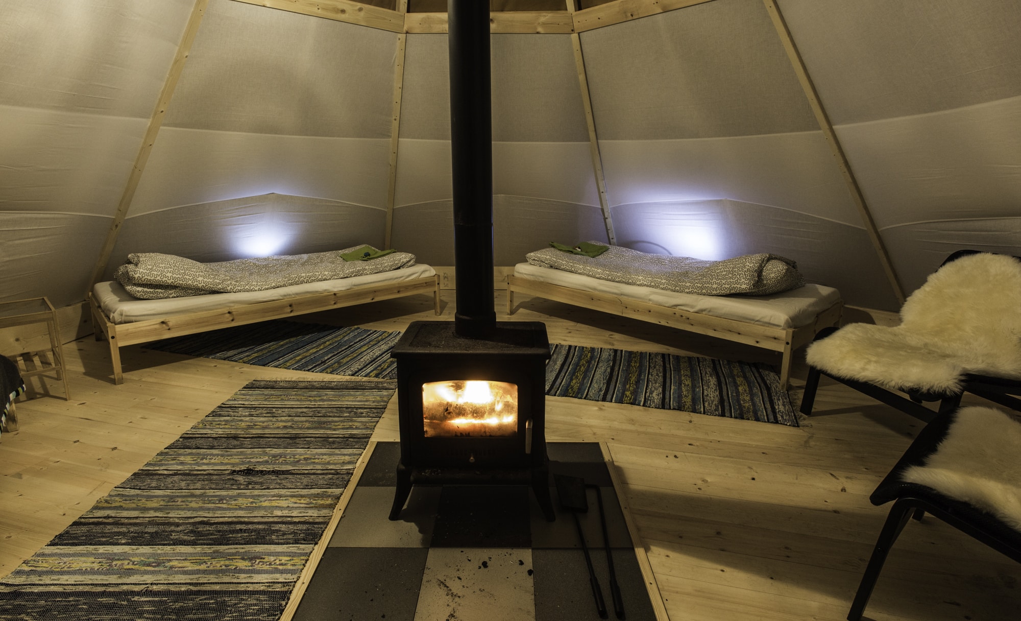 Photo de l'intérieur du tipi avec feu de cheminée au Aurora Safari Camp en Suède.