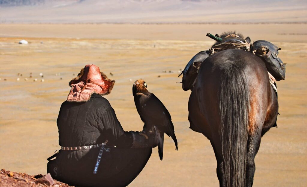 Chasseur kazakh avec son aigle et son cheval dans les steppes mongoles.