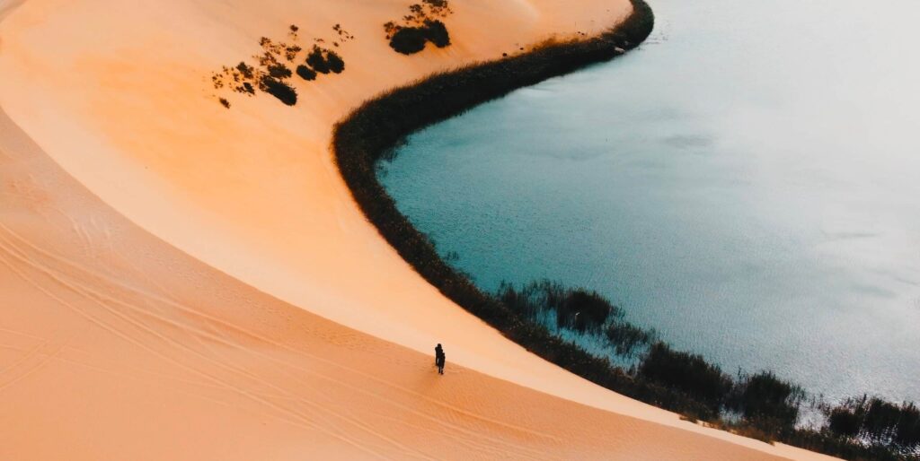 Drone,View,Of,Sand,Dune,With,Lake,In,Background.