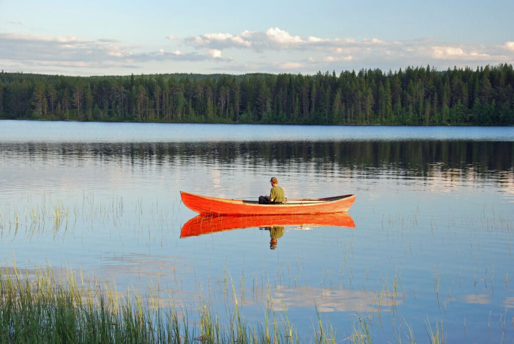 Man,Sitting,In,A,Red,Orange,Canoe,On,A,Lake