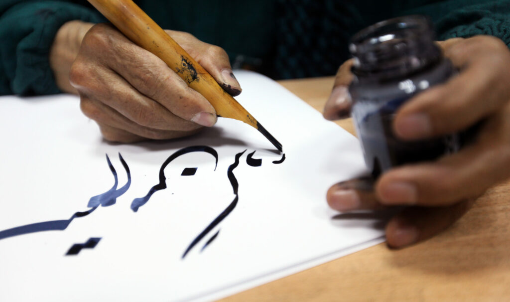 Man,Hands,Writing,Arabic,Calligraphy,With,Ink